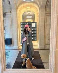 a woman taking a selfie with two poodles in front of an elevator