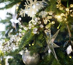 a christmas tree with ornaments hanging from it's branches and snowflakes on top