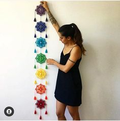 a woman standing next to a white wall holding onto a string of crochet