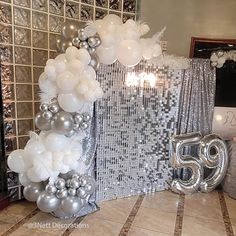 the balloon arch is decorated with silver and white balloons