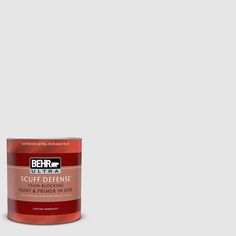 a can of red paint sitting on top of a white floor next to a wall