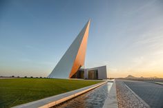 a large monument sitting on top of a lush green field next to a body of water