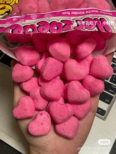 someone is holding up some candy hearts in front of their laptop computer, and it looks like they are made out of marshmallows