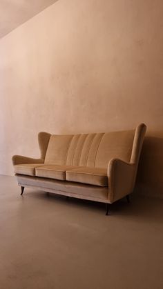 a tan couch sitting next to a wall in an empty room with no one on it