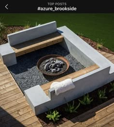 an outdoor fire pit surrounded by gravel and wooden decking, with a bowl of rocks in the center