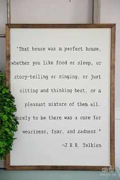 a wooden frame with a quote on it next to a potted plant and wall