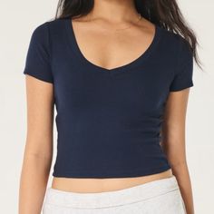 Nwt Hollister Navy Blue Cotton Blend V-Neck Baby Tee Cotton Blend V-Neck Baby Tee A Super Soft And Ultra-Comfy T-Shirt With Short Sleeves And V-Neckline. Ribbed Fabric. Slim Fit. This Item Is Available In Extended Lengths: Short - 17" Regular - 19" Long - 21" Imported. Body:57% Cotton, 38% Polyester, 5% Elastane Machine Wash Cold, With Like Colors Only Non-Chlorine Bleach Tumble Dry Low Low Iron If Needed Do Not Dry Clean Trendy Navy V-neck Top, Fitted V-neck Crop Top For Loungewear, Blue Stretch V-neck T-shirt, Navy Stretch V-neck Top, Low-cut Seamless Tops For Loungewear, Fitted V-neck Basic Tops, Seamless Low-cut Tops For Loungewear, Blue V-neck T-shirt For Loungewear, Basic V-neck Stretch Crop Top