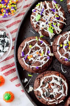 chocolate cookies decorated with white icing and sprinkles on a black plate