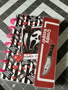 a red and black notebook with some stickers on it next to a bookmark