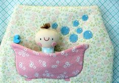 a small doll in a pink pillow with bubbles coming out of it's mouth