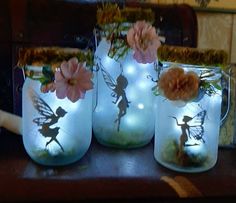 three mason jars with fairy lights and flowers in them