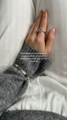 a woman's hand resting on the back of a couch with her arm wrapped in a sweater