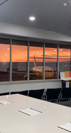 an airplane is seen through the windows of this airport lounge room at sunset or dawn