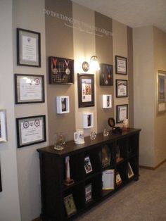 a room with several framed pictures and wine glasses on the shelf in front of it