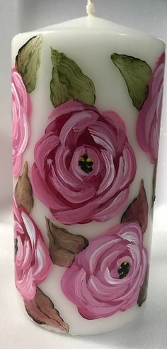 a white candle with pink flowers painted on it