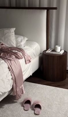 a pair of pink slippers sitting on top of a white rug next to a bed