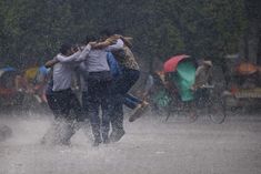 some people are walking in the rain with their arms around each other and one person is holding an umbrella