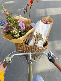 a person riding a bike with flowers in the basket on the handlebars,