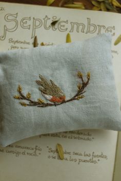 a small embroidered pillow sitting on top of an open book