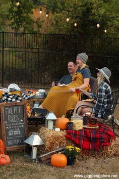 a group of people sitting on top of hay next to pumpkins and other decorations