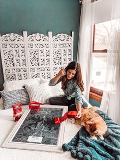 a woman sitting on top of a bed next to a cat and a framed photograph