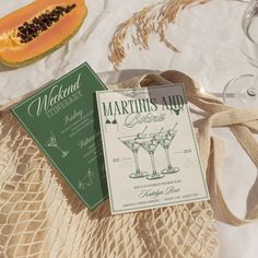 there are two menus on the table next to some wine glasses and a cantaloupe