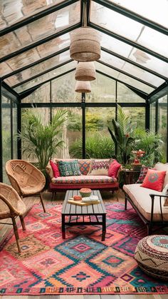 a living room filled with lots of furniture and plants inside of a glass walled building