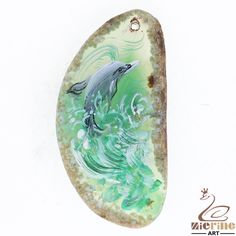 a green and white pendant with a dolphin in the water on it's side