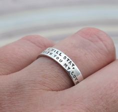 a person wearing a silver ring with words on it