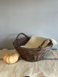 a wicker basket sitting on top of a table next to a pumpkin