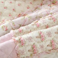 a pink and white quilted crib with flowers on the top, along with checkered sheets