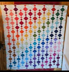 a multicolored quilt hanging from the side of a wall next to a door