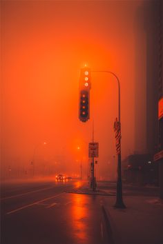 a traffic light sitting on the side of a road next to a tall building in the fog