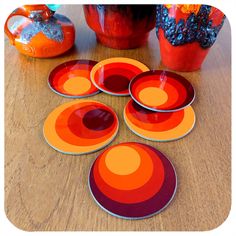 six orange and red plates sitting on top of a wooden table