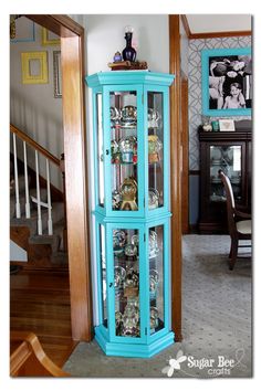 a tall blue curio cabinet sitting in the corner of a room next to stairs