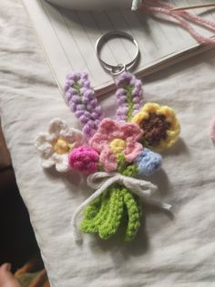 a crocheted keychain with flowers on it and a notepad in the background