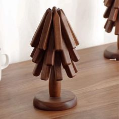 a small wooden christmas tree sitting on top of a table next to a coffee cup