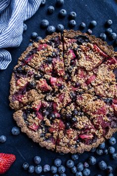 a blueberry crumb pie with fresh berries around it