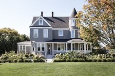 a large gray house sitting on top of a lush green field