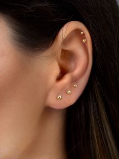 a close up of a woman's ear with three small gold dots on it