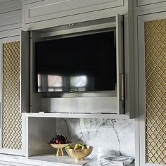 a tv mounted to the side of a cabinet in a room with marble counter tops