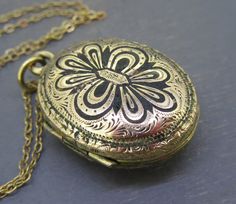 "Antique oval locket with a gold tone finish and set with some black enamel, a small bit of enamel chipping/loss.  Opens and closes and stays closed.  Has one glass frame inside. Small ding on the back. Comes with a brand new 16\" gold filled chain. Visit Ribbons Edge for more great pieces of vintage and antique jewelry!" Cameo Necklace Vintage, Black Medallion Locket Necklace As A Gift, Antique Finish Oval Locket Necklace In Vintage Style, Black Enamel Oval Necklace As Gift, Oval Black Enamel Jewelry Gift, Oval Etched Locket Necklace As Gift, Vintage Oval Pendant Locket Necklace With Antique Finish, Oval Etched Locket Necklace For Gift, Ornate Oval Locket Necklace From Vintage Collection