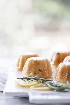 small pastries on a white plate with lemon wedges and rosemary sprigs