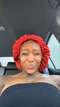 a woman with a red head scarf on her head sitting in the back seat of a car