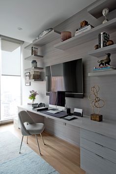 a living room with a large flat screen tv mounted to the wall next to a white chair