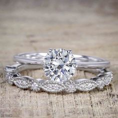 a white gold engagement ring set with an oval diamond center and twisted band, on top of a piece of wood