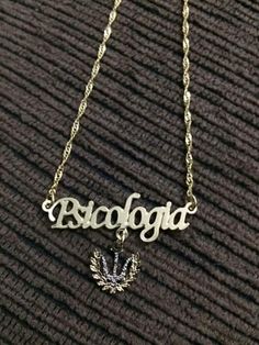 a gold necklace with the word's name on it and a small leaf charm hanging from