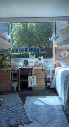 a bedroom with two bunk beds and a desk in front of a window that looks out onto the street