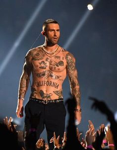 the tattooed man is standing in front of an audience