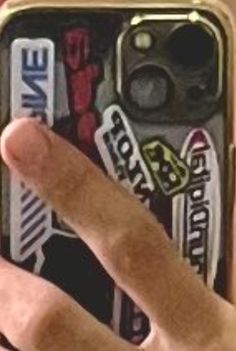 a person holding up a cell phone with stickers on it